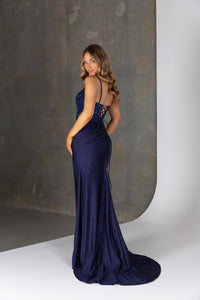 Woman wearing a navy blue evening gown against a neutral background