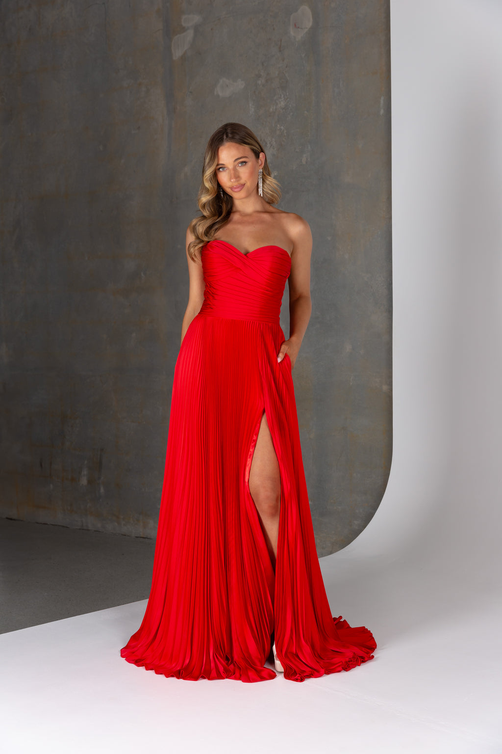 Hera formal dress by Tania Olsen – strapless sunray pleated satin gown with corset bodice, leg split and side pockets.