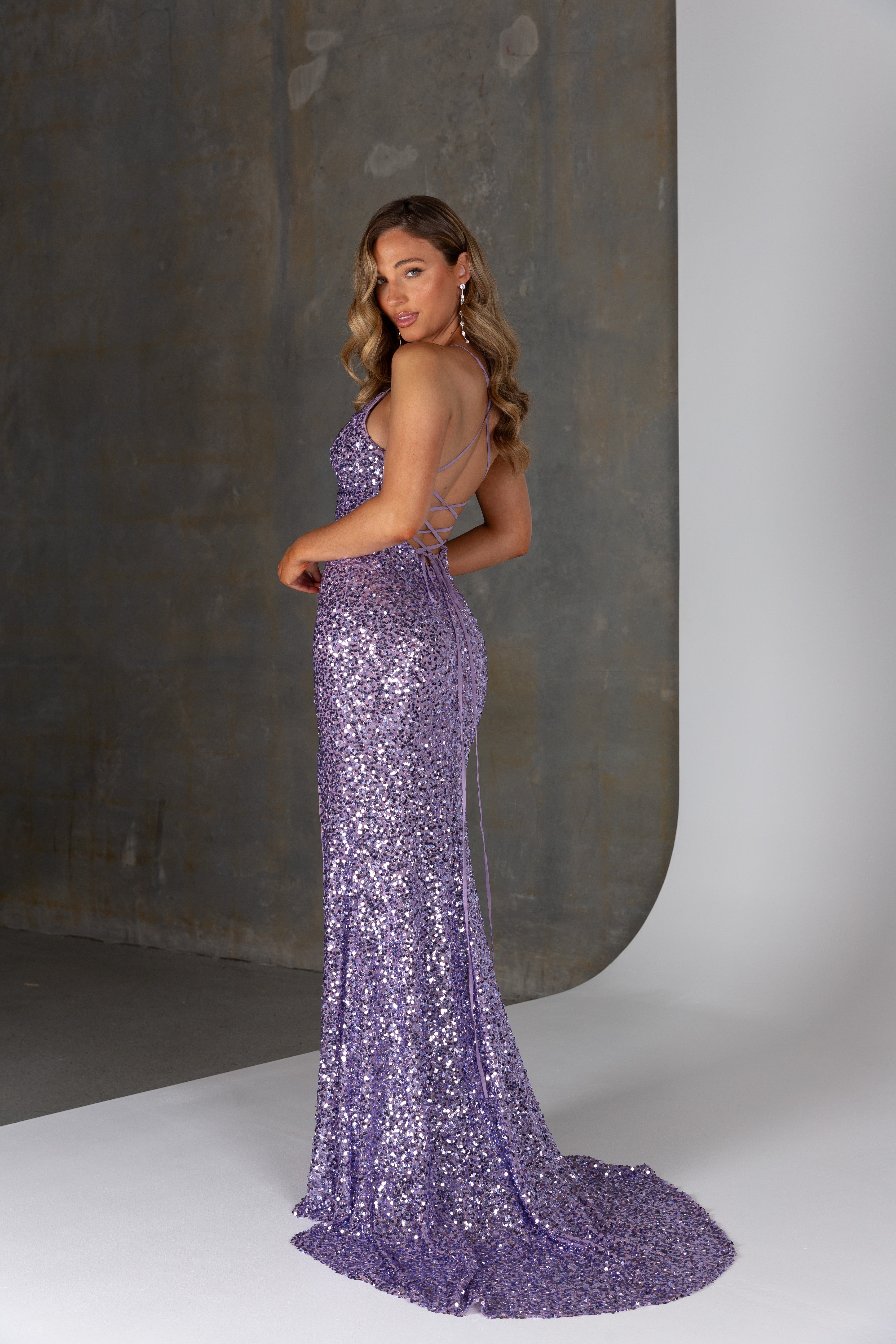 Woman wearing a purple sequin gown against a neutral background